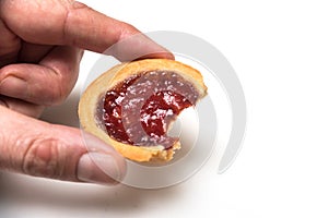 crunched mini tartlets with strawberry jam in hand on white background