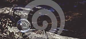 Closeup of a crystal ball with the reflection of surroundings on it on the rock under the sunlight