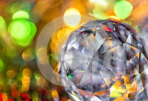 Closeup of crystal glass faceted ball on background of festive lights. Abstract festive, christmas or interior background.