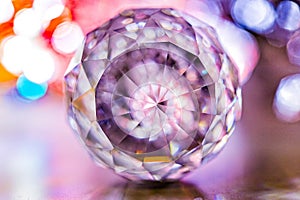 Closeup of crystal glass faceted ball on background of festive lights. Abstract festive, christmas or interior background.