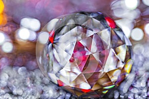 Closeup of crystal glass faceted ball on background of festive lights. Abstract festive, christmas or interior background.