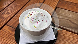 Closeup of cup of cappuccino with sprinkles on top of cream