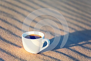 Closeup cup of cofee on a sand