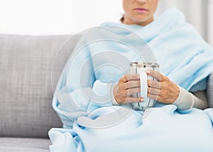 Closeup on cup with hot beverage in hand of ill woman