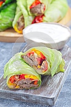 Closeup cut of beef and vegetable cabbage leaves wraps, served with plain yogurt, vertical