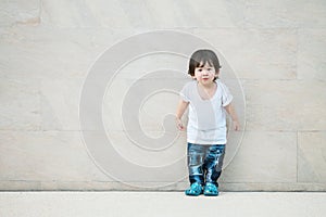 Closeup cute asian kid stand on marble stone wall textured background with copy space