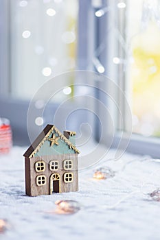 Closeup cute Christmas winter house with golden star indoor with festive garland and blurred bokeh background near window in