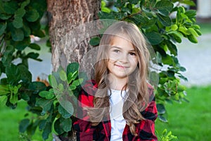 Closeup of cute little girl with long hair. Playful little girl portrait in park, smiling and playing at nature. Childhood concept