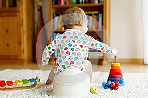 Closeup of cute little 12 months old toddler baby girl child sitting on potty.