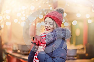 Closeup of cute lovely girl in red hat drinking hot coffee outdoors in winter snow day. standing at the street and drinking hot