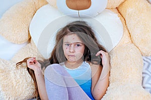 Closeup of cute sad little girl near the teddy bear. Varicella virus or Chickenpox bubble rash on child