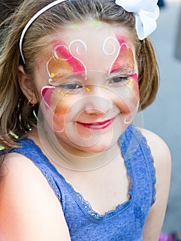 Closeup of cute smiling little girl with butterfly face makeup