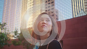 Closeup cute woman look back on city building. Portrait asian girl on sunlight.