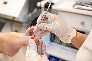 Closeup of cuticle removal on toes. Pedicure procedure, nipping cuticles