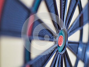 Closeup of a dartboard in focus, the red target area in the center of the board clearly visible