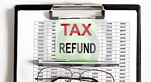 Closeup of the deadline time of TAX REFUND and glasses and pen
