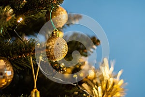 Closeup of a decorative ornament hanging from the Christmas tree covered with lights