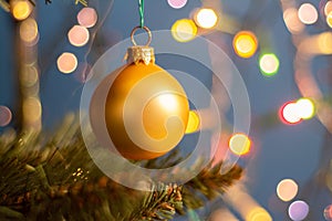 Closeup of a decorative ornament hanging from the Christmas tree covered with lights