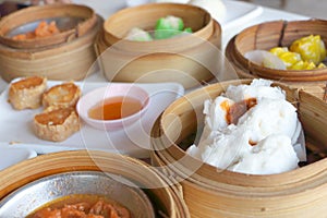 Closeup deep Chinese steamed red pork bun break can see pork inside in bamboo basket in dim sum set, Chinese restaurant food