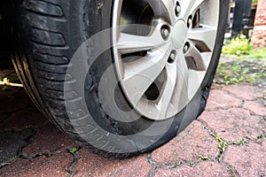 Closeup of deflated flat car tire due to rupture at the side of the wheel