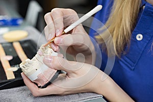 Closeup of a dental technician applying porcelain to a mold