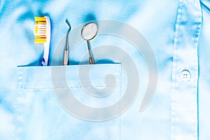 Closeup of dental tool, toothbrush and a mirror in white medical uniform pocket. Oral dental health concept