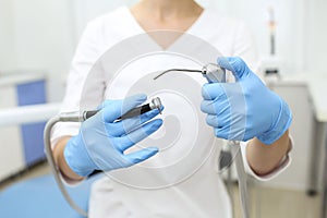 Closeup of dentist tools in hands of womn in blue glowes. Selective focus