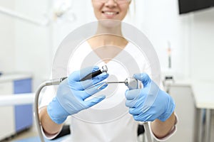 Closeup of dentist tools in hands of womn in blue glowes. Selective focus