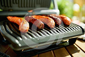 Closeup on desk with electric grill and grilled sausages