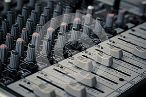 Closeup and detail of audio mixing console with faders and knobs