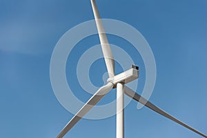 Closeup detail back view of new white modern wind turbine farm power generation station against clear blue sky on day