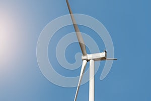 Closeup detail back view of new white modern wind turbine farm power generation station against clear blue sky on day