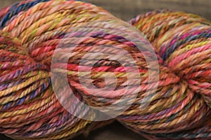 Closeup detail of colourful hand spun sheep wool merino fibres, rolled up in a yarn ball skein.