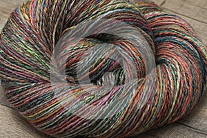 Closeup detail of colourful hand spun sheep wool merino fibres, rolled up in a yarn ball skein.