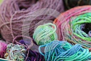 Closeup detail of colourful hand spun sheep wool merino fibres, rolled up in a yarn ball skein.