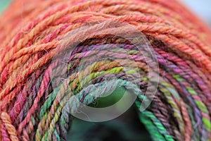 Closeup detail of colourful hand spun sheep wool merino fibres, rolled up in a yarn ball skein.