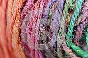 Closeup detail of colourful hand spun sheep wool merino fibres, rolled up in a yarn ball skein.