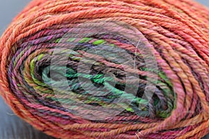 Closeup detail of colourful hand spun sheep wool merino fibres, rolled up in a yarn ball skein.