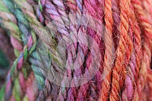 Closeup detail of colourful hand spun sheep wool merino fibres, rolled up in a yarn ball skein.