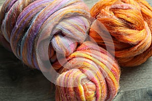 Closeup detail of colourful hand spun sheep wool merino fibres, rolled up in a yarn ball skein.