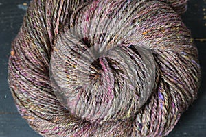 Closeup detail of colourful hand spun sheep wool merino fibres, rolled up in a yarn ball skein.