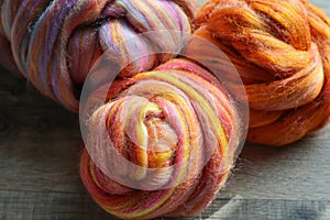 Closeup detail of colourful hand spun sheep wool merino fibres, rolled up in a yarn ball skein.