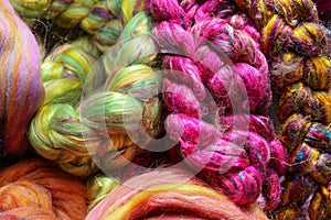 Closeup detail of colourful hand spun sheep wool merino fibres, rolled up in a yarn ball skein.