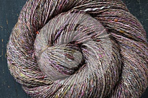 Closeup detail of colourful hand spun sheep wool merino fibres, rolled up in a yarn ball skein.