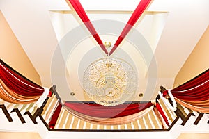 Closeup detail of an elegant chandelier and red drapes