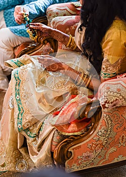 Closeup detail of an Indian bride and groom wearing beautiful colorful garments