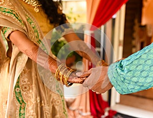 Closeup detail of an Indian bride and groom wearing beautiful colorful garments holding hands