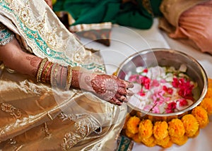 Closeup detail of an Indian bride wearing beautiful colorful garments and henna tatto