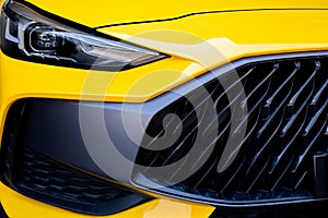 Closeup detail of yellow luxury car. Electric vehicle with modern technology. Expensive car. Shiny headlight of sport and modern