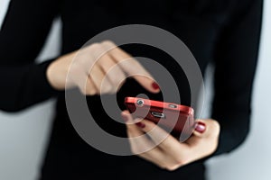 Closeup detail of young woman holding a red cell phone with camera using a touchscreen with apps